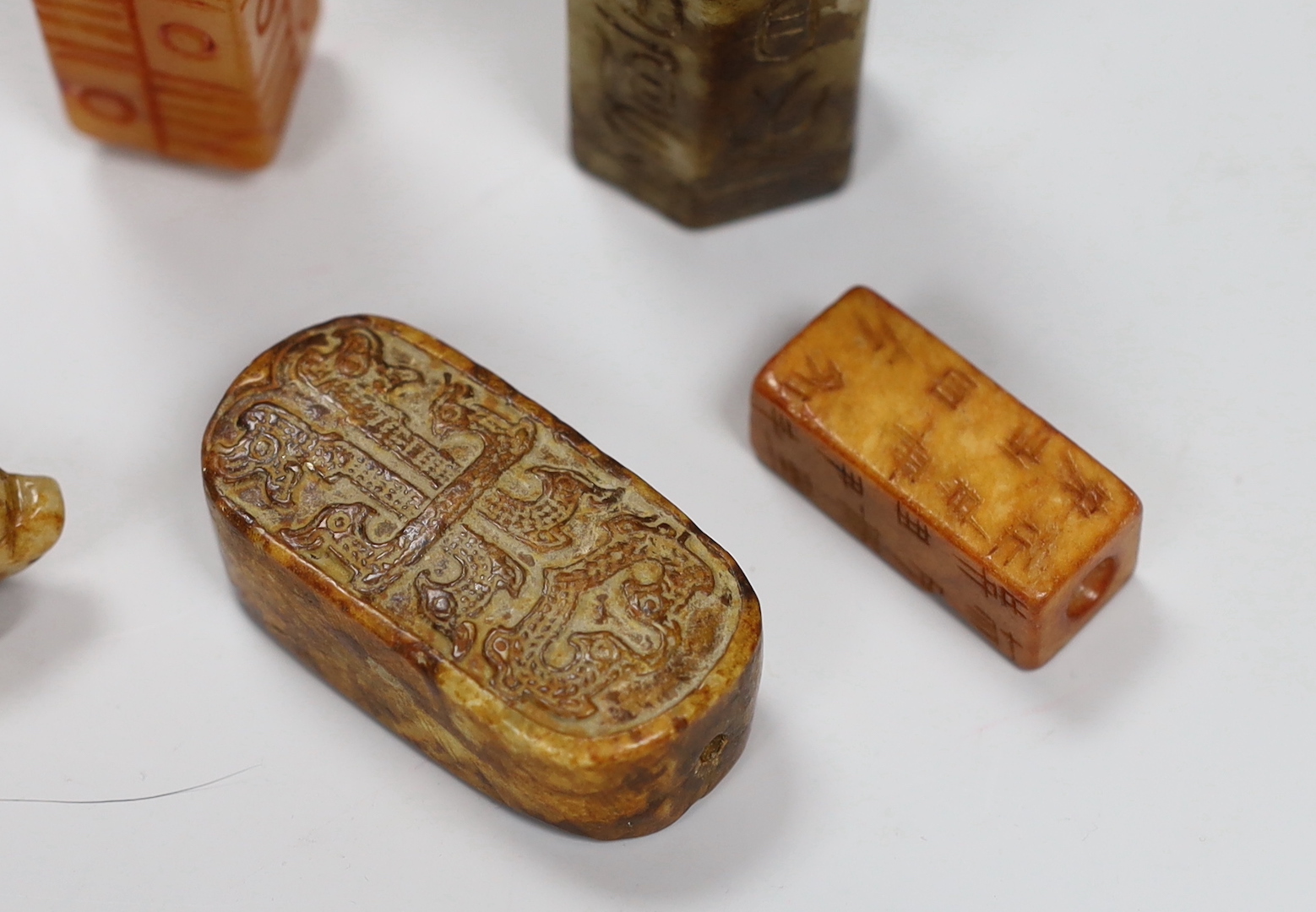 Eight Chinese archaistic jade or hardstone pendants/beads with carved decoration, the largest 9cm wide